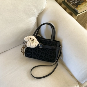 Elegante borsa leopardata con ciondolo a cane e tracolla su un divano morbido