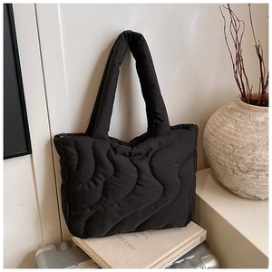 Detail of black quilted tote bag with wave stitching and soft padded handle
