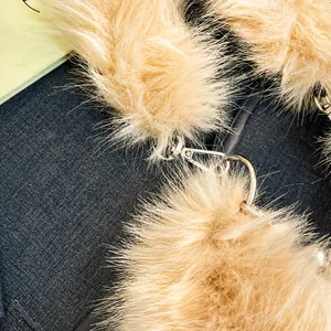 Detailed close-up of a plush beige fur scarf featuring a premium silver metal hook closure
