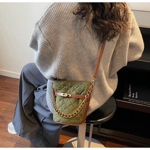Détail du sac seau matelassé vert avec chaîne dorée et fermeture en cuir brun