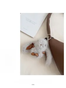 Detail of grey plush bunny charm with leather trim on a luxury dark brown handbag