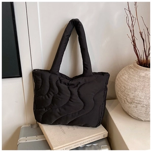 Detail of black quilted shoulder bag with wave pattern stitching and soft texture