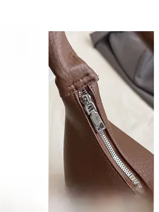 Detailed macro view of the silver metal zipper on premium brown lychee pattern leather
