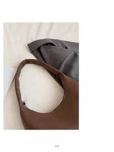 Detail of brown lychee texture leather crescent shoulder bag with silver metal zipper
