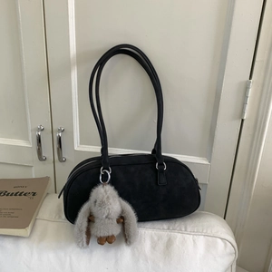 Detail of black suede Boston bag with slim handles and a plush grey rabbit charm