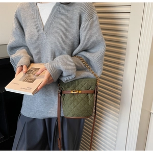 Detail of green quilted bucket bag with gold twist lock and chain strap on a model