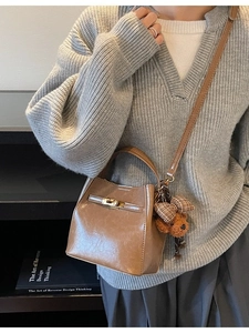 Borsa a secchiello vintage marrone con ciondolo a forma di orso su maglione grigio