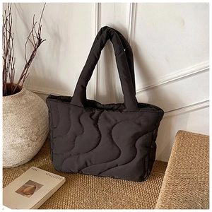 Detailed view of the black quilted texture and wavy stitching on this padded tote bag