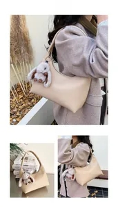 Close-up of beige lychee leather hobo bag with a plush rabbit charm accessory