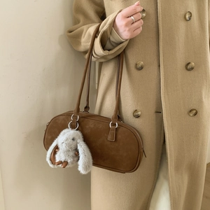 Detail of a dark brown suede Boston bag featuring a cute plush bunny charm on the handle