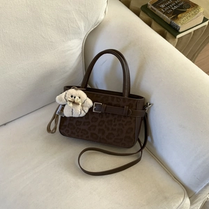 Dettaglio borsa leopardata con cinturino a fibbia e ciondolo a forma di cucciolo