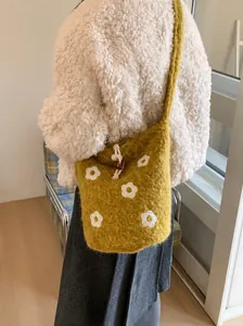Detail of mustard yellow plush bucket bag with white floral embroidery and drawstring closure