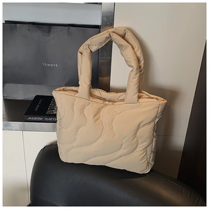 Close-up of beige quilted nylon handbag with wave patterns and soft padded handle