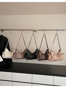 Hanging display of assorted pleated hobo bags in cream, beige, black, and brown tones