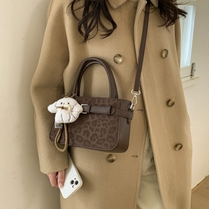 Dettaglio borsa leopardata con ciondolo a forma di cucciolo bianco e tracolla sottile