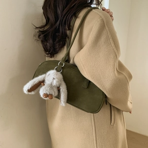 Detailed side view of an olive green suede shoulder bag with a white bunny charm