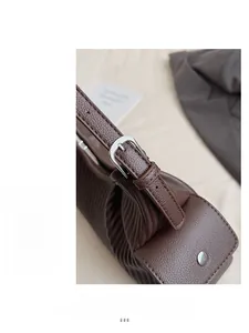 Detail of silver metal buckle and fine stitching on dark brown lychee leather handbag