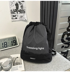 Dettaglio dello zaino multifunzionale con coulisse, logo Traveling Light e motivo a scacchi