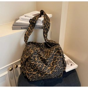 Detail of a leopard print canvas crossbody bag featuring a wide adjustable black strap
