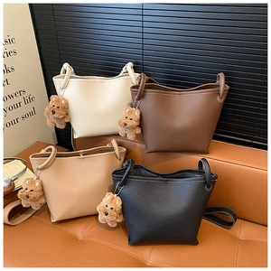 Detailed shot of four lychee texture leather bucket bags with plush bear charms