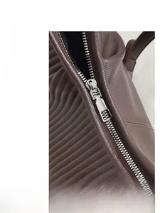 Detail of high-quality smooth silver zipper and dark brown lychee grain leather texture