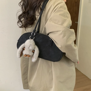 Chic black matte pillow bag with cute rabbit pendant worn with a stylish trench coat