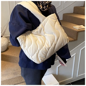 Detail of cream quilted puffer shoulder bag showing wavy texture and wide strap