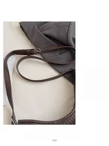 Close-up of adjustable dark brown leather shoulder strap with silver buckle and litchi texture