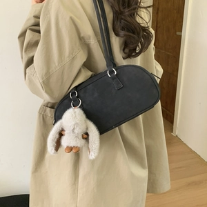 Detail of matte black cylinder shoulder bag with a cute white bunny plush charm