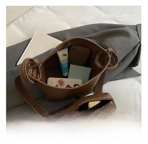 Detailed view of the brown leather bucket bag interior showing a matching pouch and capacity
