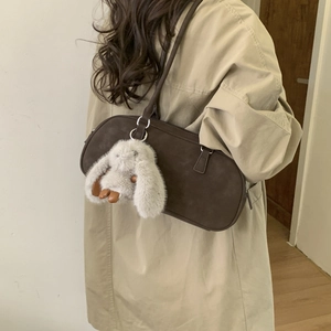 Detail of dark brown rectangular shoulder bag with cute white plush rabbit charm