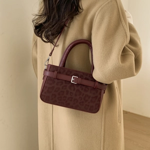 Modella indossa una borsa bordeaux con stampa leopardata e una fibbia argentata