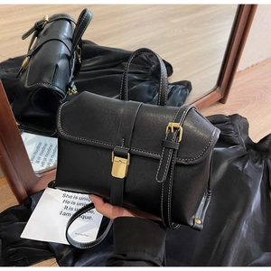 Detail view of black faux leather bag with contrast white stitching and gold metal buckle