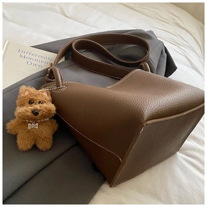 Detailed close-up of dark brown lychee leather bucket bag with dog charm and stitching