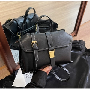 Detail view of black vintage crossbody bag with white stitching and gold buckle