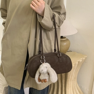 Detail of dark brown leather baguette bag with silver hardware and plush bunny charm