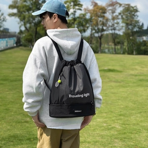 Dettaglio dello zaino a scacchi con coulisse, stampa Traveling Light e ciondolo tennis