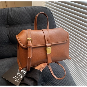 Detail view of brown vintage leather crossbody bag with white contrast stitching and hardware