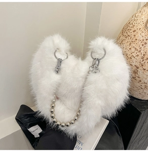 Detailed view of white faux fur handbag featuring silver metallic bead chains and large rings
