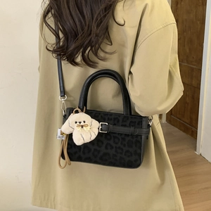 Dettaglio della borsa leopardata con ciondolo a cane di peluche beige e fibbia decorativa