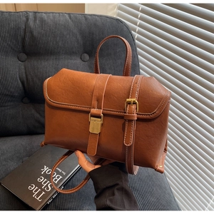 Detail of vintage brown leather handbag with antique gold clasp on a cozy sofa