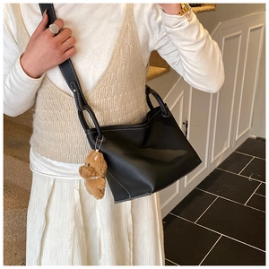 Black pebbled leather bucket bag with white contrast stitching and a plush bear charm