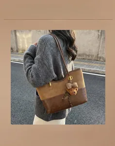 Close-up of winter brown tote bag with teddy bear charm and large capacity on grey sweater
