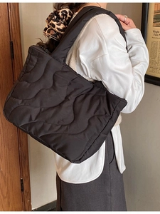 Chic black quilted shoulder bag featuring a padded wave stitch design and wide strap