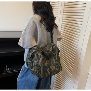 Detail of a camouflage canvas crossbody bag featuring side cargo pockets and large capacity
