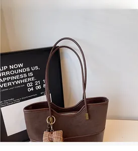 Close-up of vintage brown suede patchwork tote bag with a plaid bow charm detail