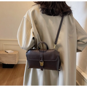 Close-up of vintage dark brown crossbody bag with matte faux leather and gold buckle