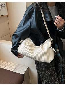 Detailed view of cream-white pleated hobo bag with vertical folds and adjustable strap