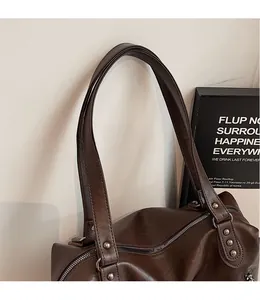 Detail of vintage brown leather tote bag showing smooth shoulder strap and silver rivets
