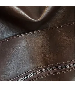 Macro detail of dark brown leather texture and precision stitching with metal zipper